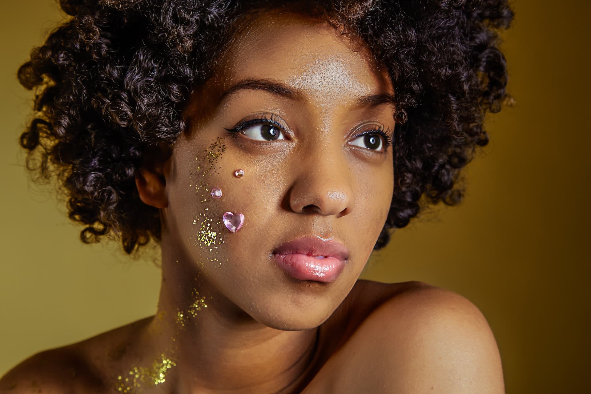 beautiful black woman posing for a portrait with hearts and glitters on her face