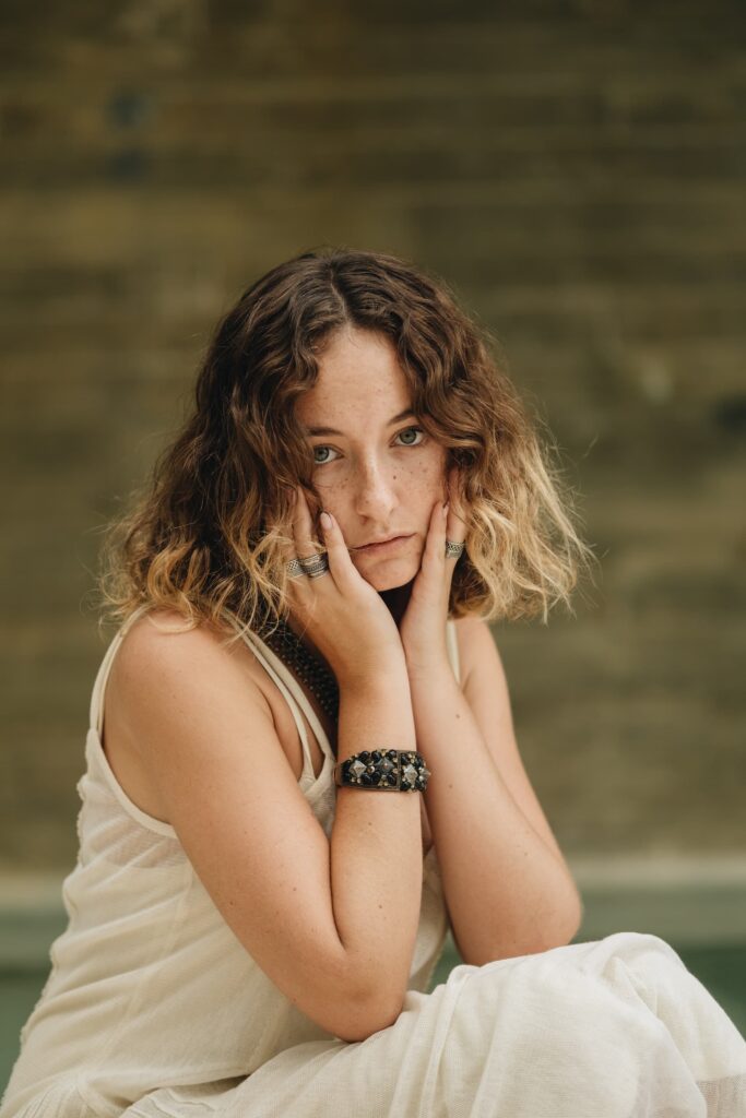 woman sitting outside holding her face in her hand