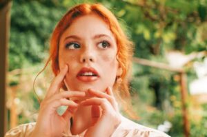 Beautiful red head woman posing for a portrait touching her face